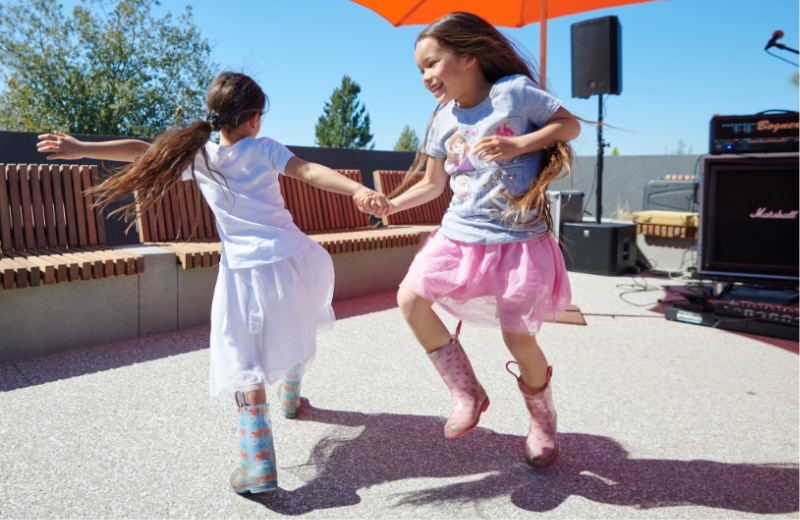 Little girls in rain boots holding hands and dancing